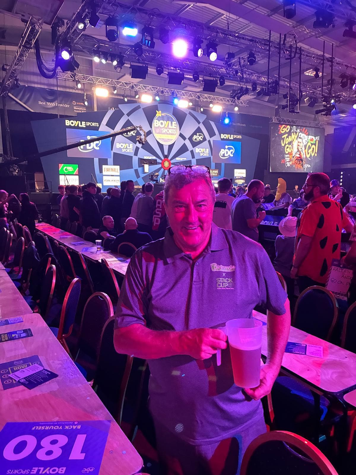 A Drinksmate team member holding a pint in a Stack Cup jug at a PDC darts event
