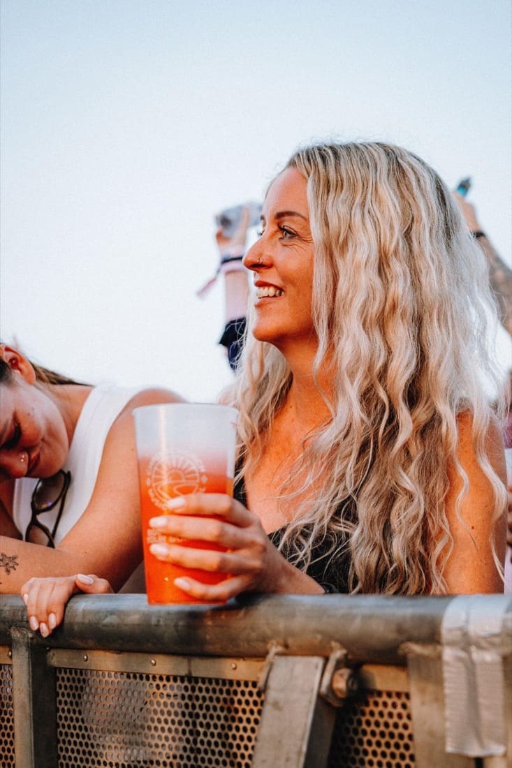 Festival-goer at the front barrier holding a branded reusable pint cup