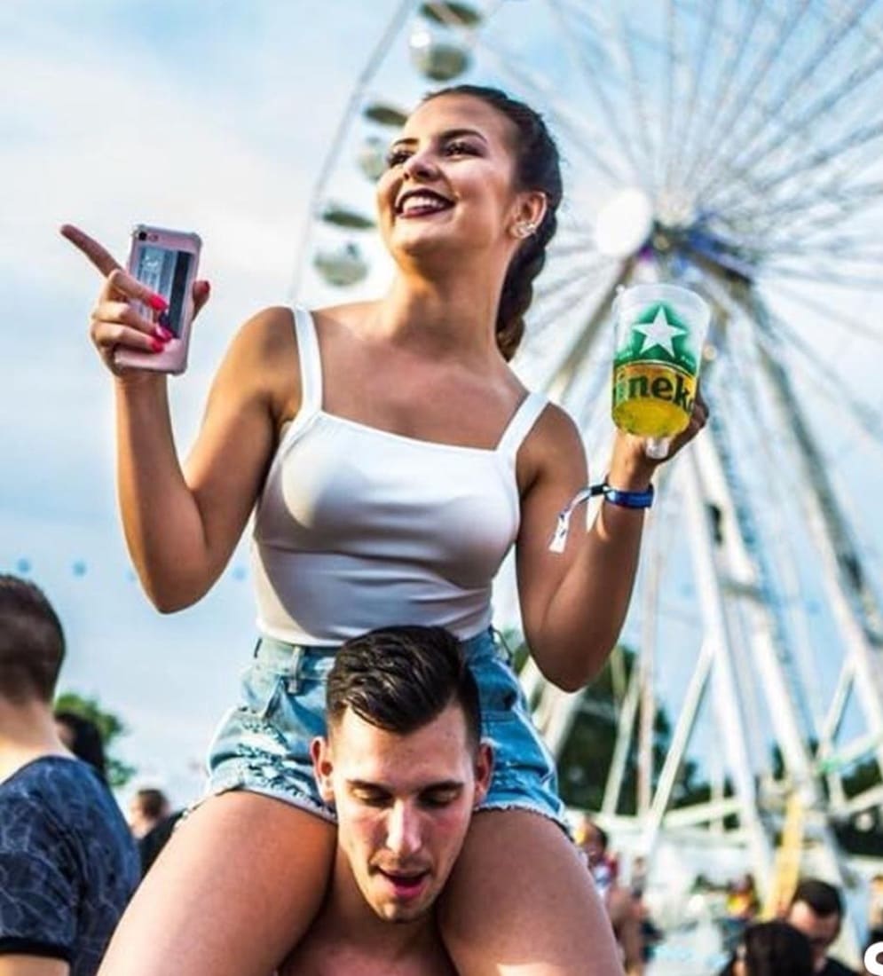 Festival crowd in front of a ferris wheel, branded pint cup raised