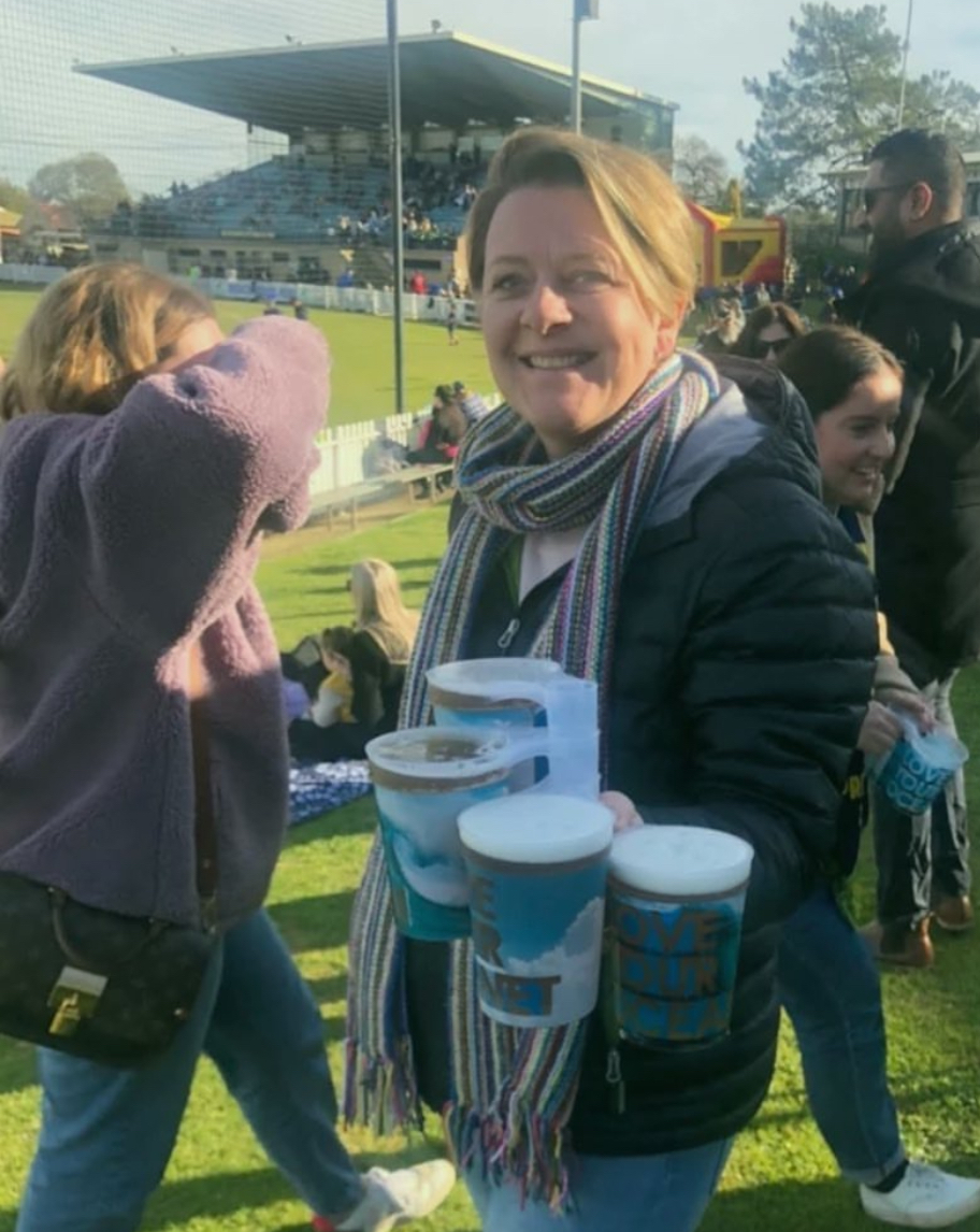 A visitor carrying several branded reusable cups at an outdoor event