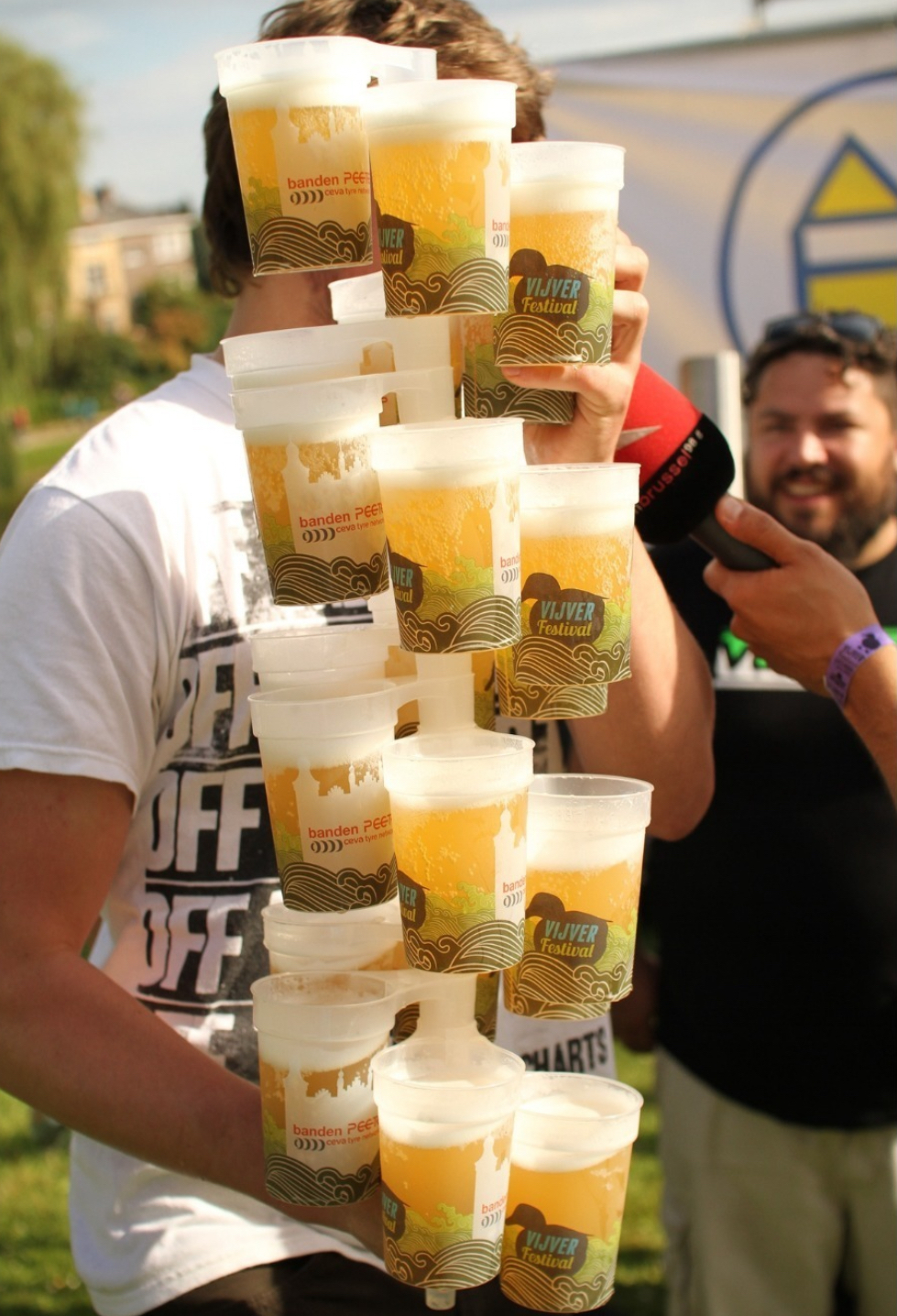 A large stack of branded reusable festival cups held at an outdoor event